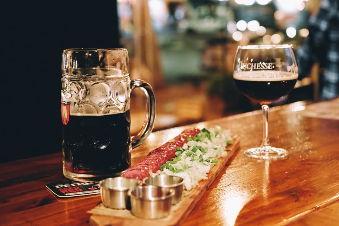 Bière brune et planche de charcuterie posées sur le bois du Kraken Bar.